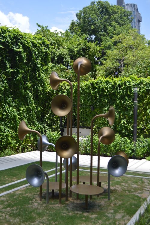 Free Elegant brass sculpture displayed in a lush urban garden setting. Stock Photo