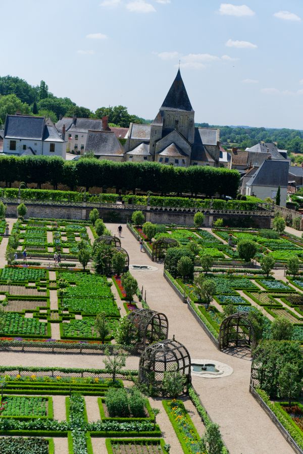 Des visiteurs flânent dans le potager de Villandry, les toits du village en arrière-plan