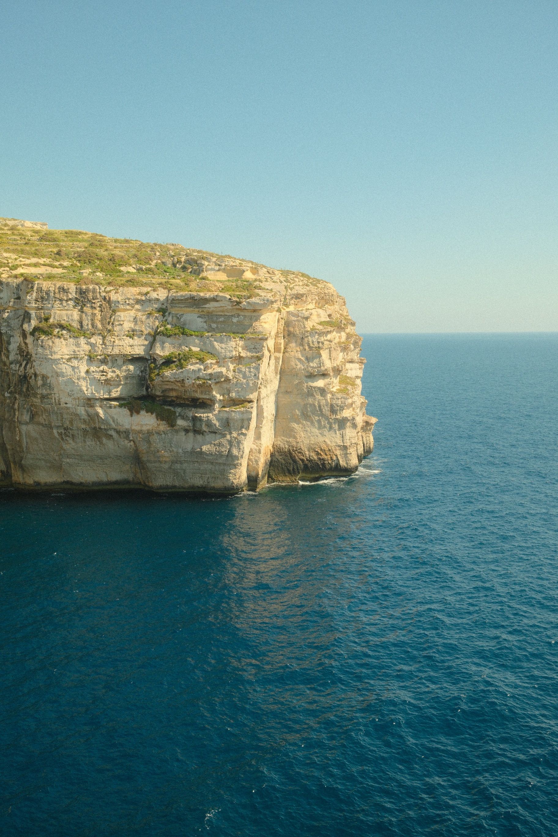 Scenic view of a sunlit cliff and blue sea in Malta, perfect for travel and nature themes.