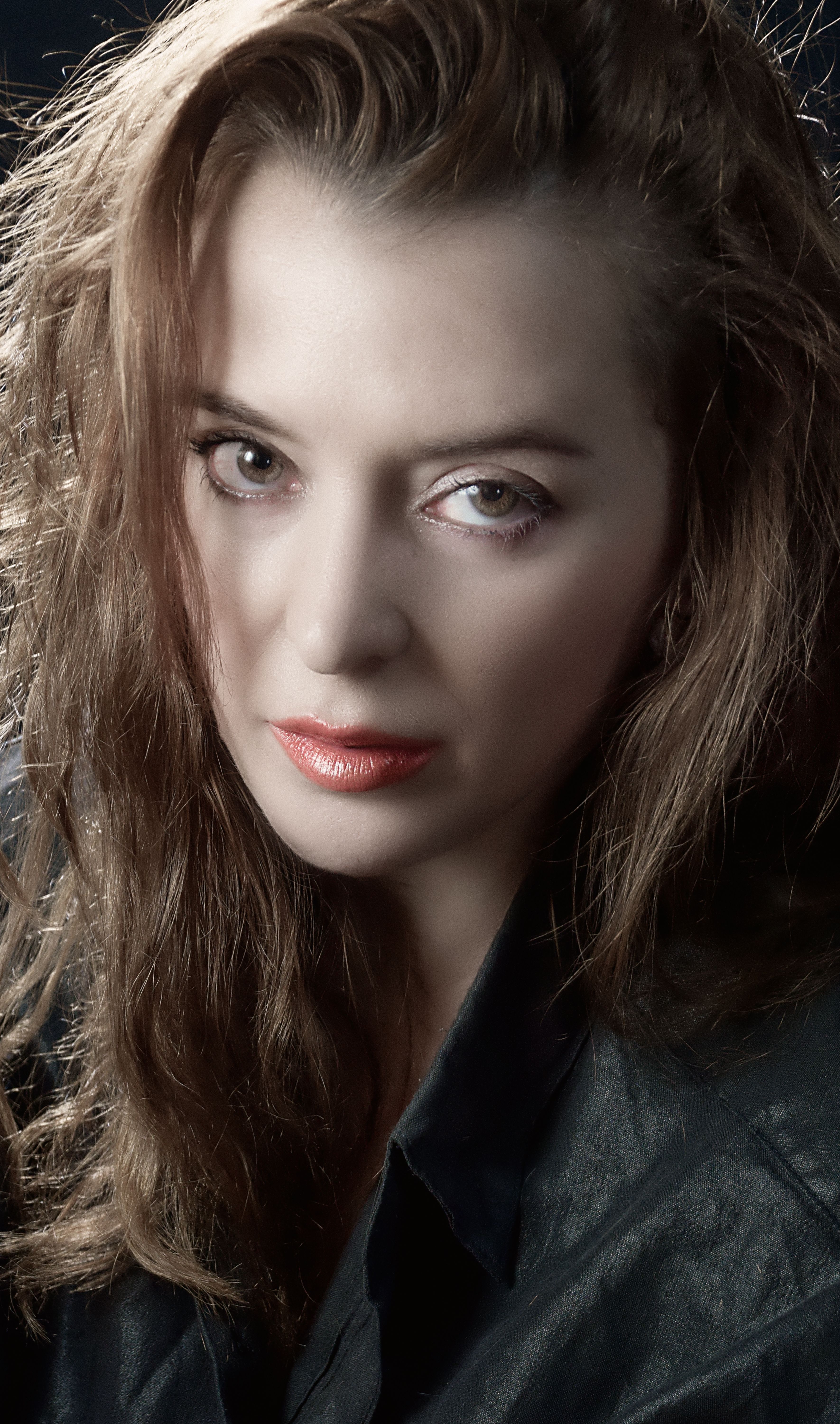 Close-up portrait of a woman with moody lighting and intense gaze, highlighting natural beauty.