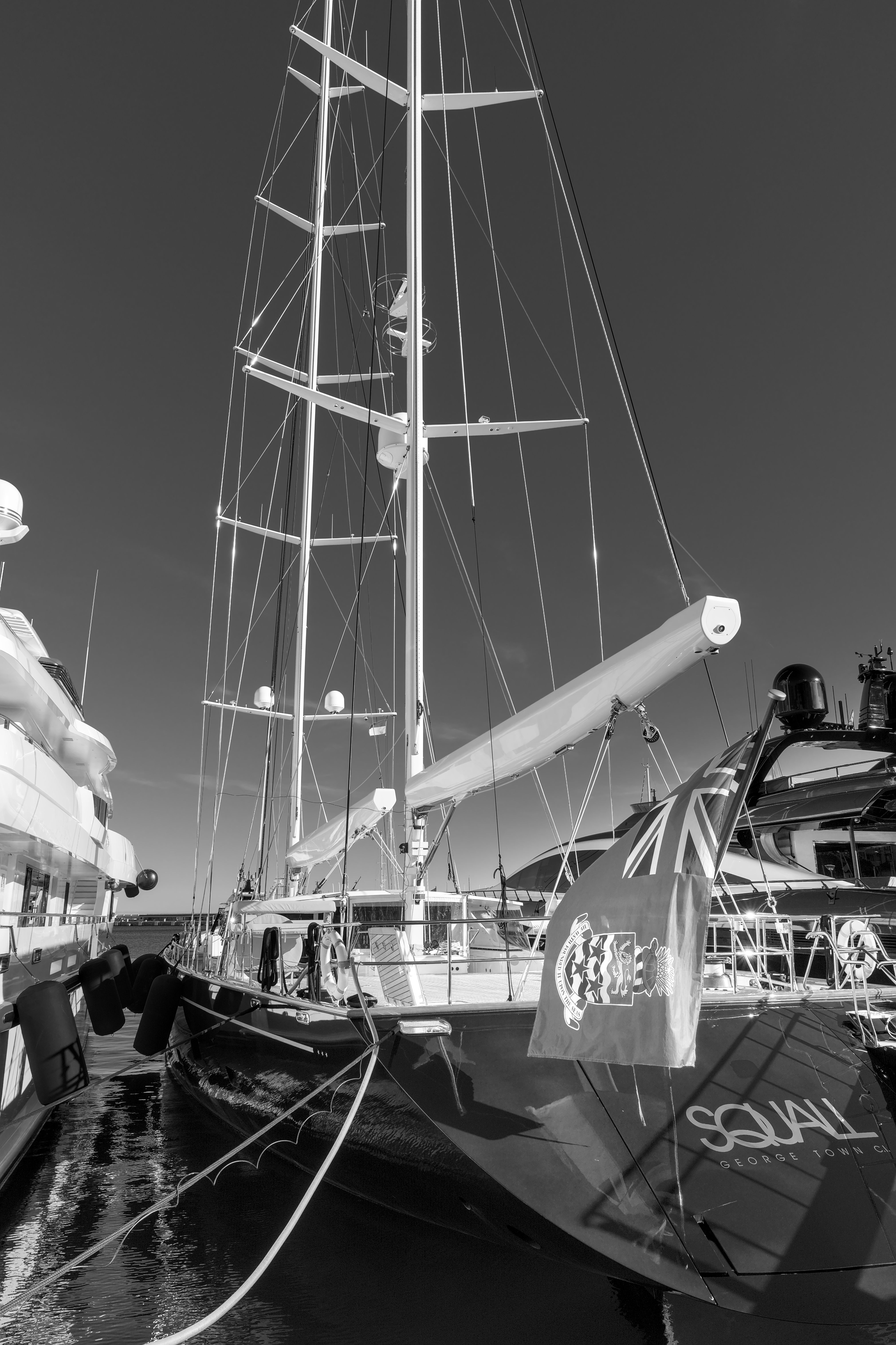 Elegant sailboat moored in Monaco's harbor, captured in striking black and white.