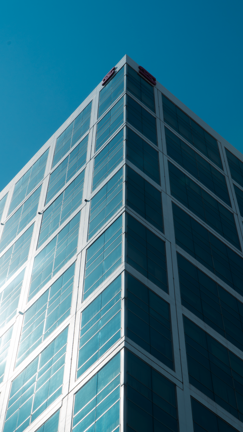 Free Low angle view of a modern glass skyscraper against a bright blue sky. Stock Photo