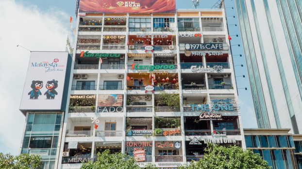 A lively apartment building facade in Vietnam with colorful cafe signs.