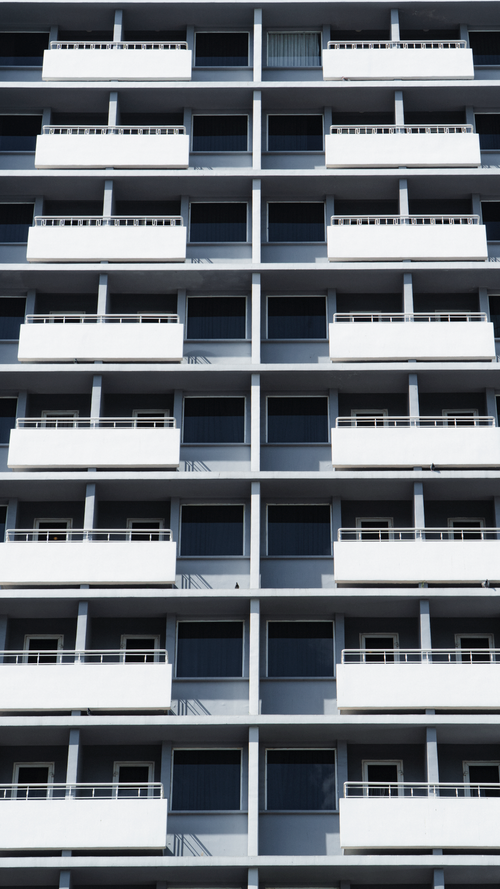 Free Vertical view of a modern building facade with symmetrical balconies and minimal design. Stock Photo