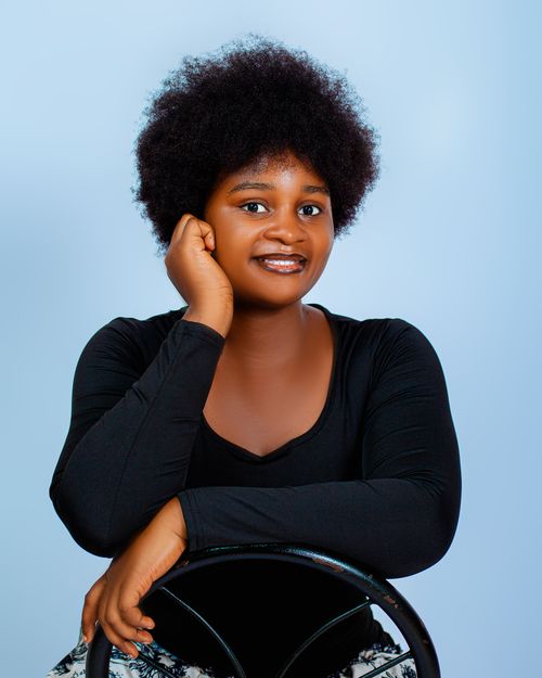Free Portrait of a confident woman with natural afro hairstyle, smiling indoors. Stock Photo