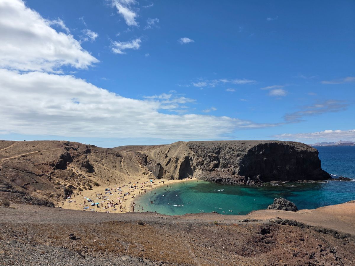 Vedere aeriană a plajei Papagayo din Lanzarote, cu apă turcoaz între faleze joase
