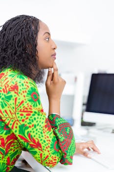 一位穿着亮绿色图案连衣裙的非洲妇女正专注于办公桌前