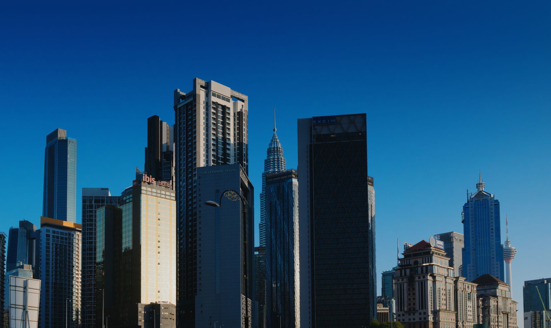 Stunning view of Kuala Lumpur's skyline featuring iconic towers under a clear blue sky.