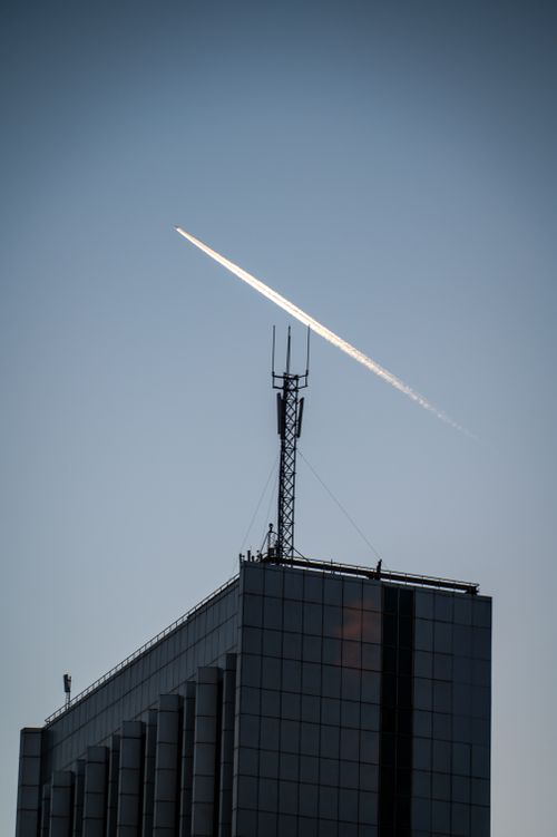 Free A jet contrail arches over a modern building in Baku, Azerbaijan against a clear blue sky. Stock Photo