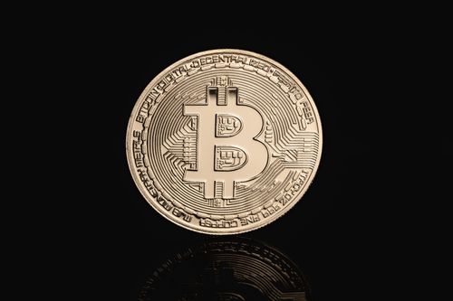 Free A detailed close-up of a gold Bitcoin coin against a dark background, emphasizing cryptocurrency visuals. Stock Photo