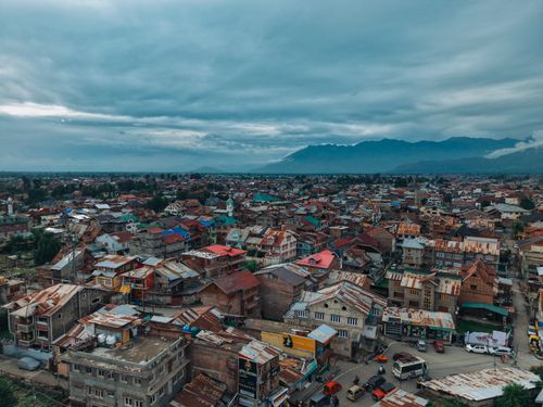 Free Stunning aerial view of Srinagar city with dramatic clouds and distant mountains, capturing the vibrant urban landscape. Stock Photo