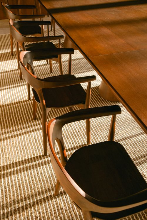 Free Warmly lit row of wooden dining chairs against a textured rug. Stock Photo