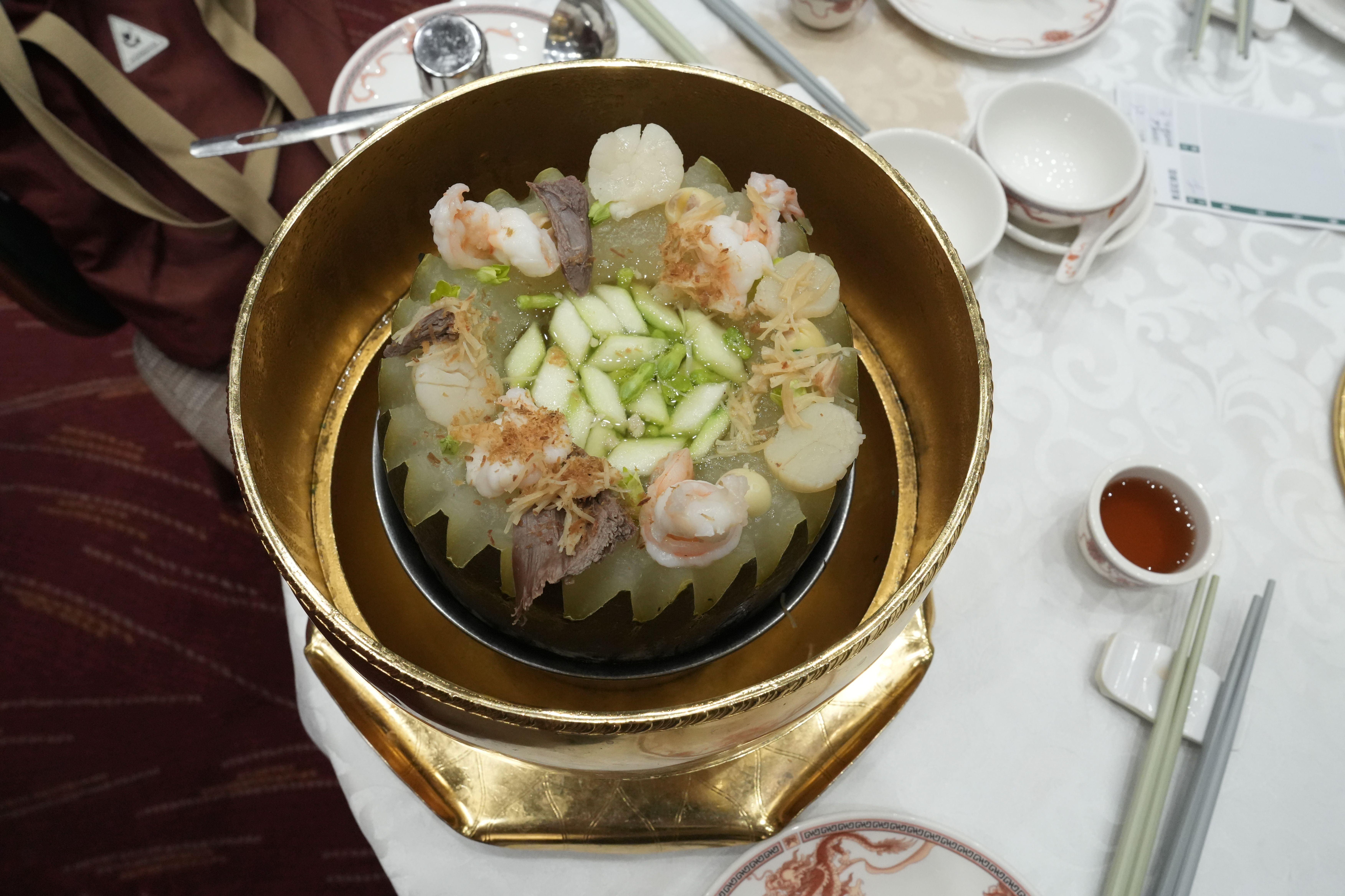 A delectable Chinese dish featuring prawns and melon elegantly served in a golden bowl.