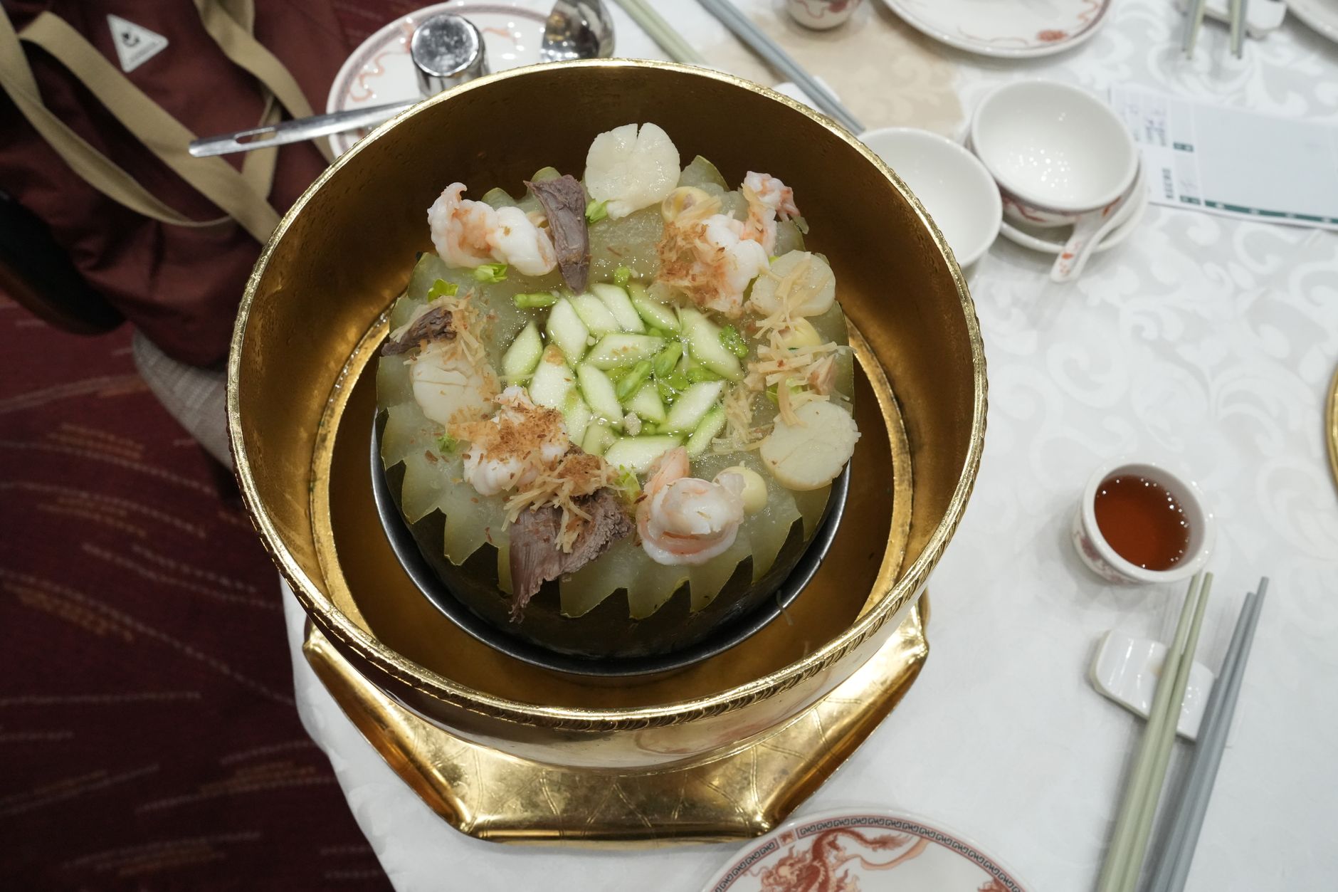 A delectable Chinese dish featuring prawns and melon elegantly served in a golden bowl.