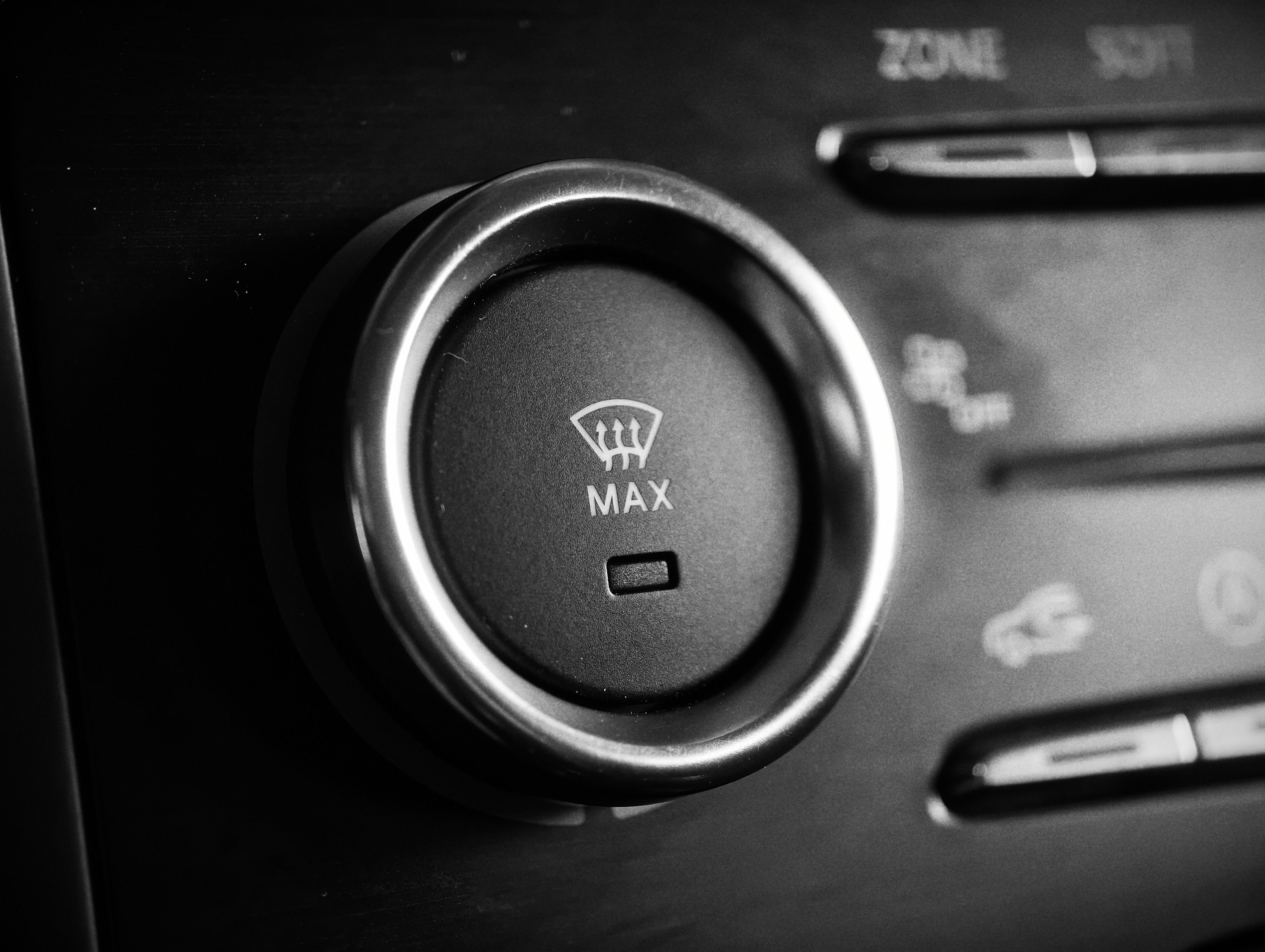 Detailed close-up of a car climate control knob in black and white, captured for automotive enthusiasts.