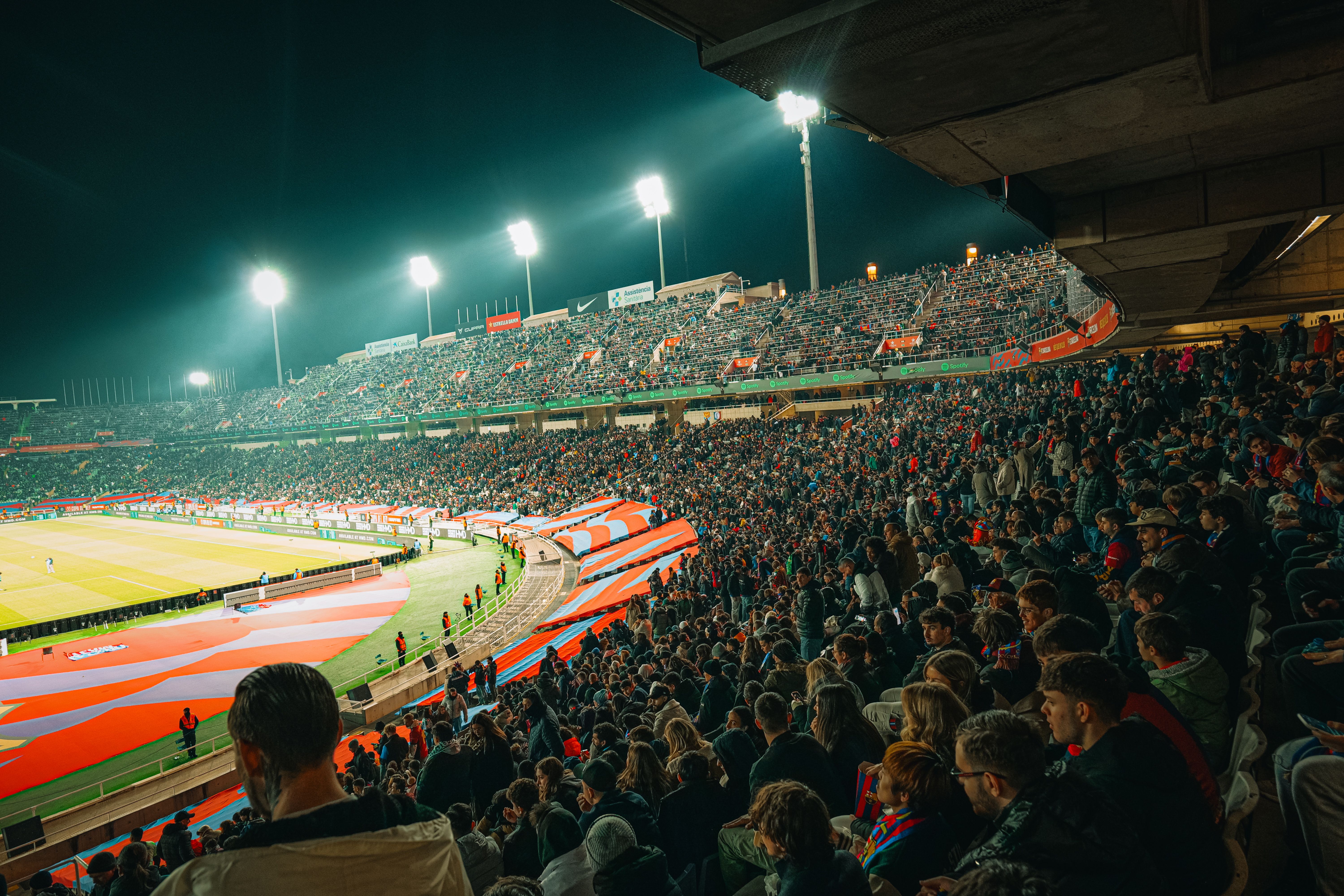 NFL photo featuring A vibrant nighttime soccer match with a packed stadium full of enthusiastic fans.