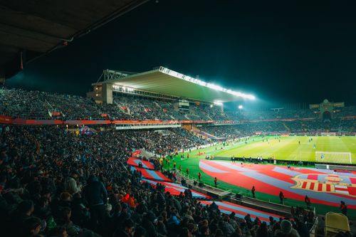 Free A crowded night-time football match in a brightly lit and bustling stadium, full of energy. Stock Photo