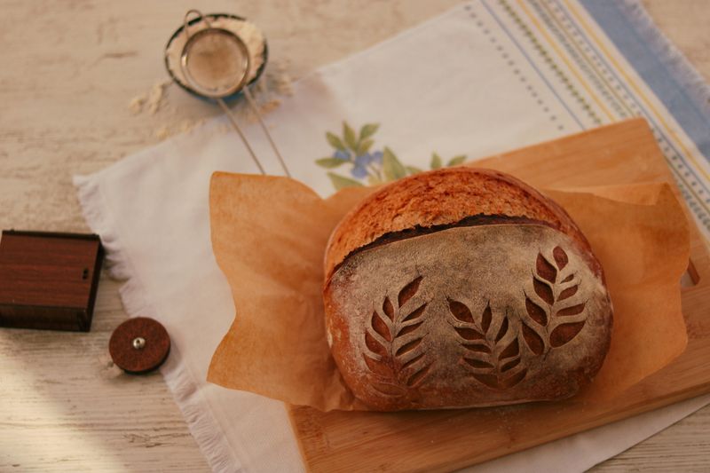 Scored sourdough loaf rising in a hot bakery oven