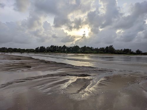 Free Peaceful beach at sunset with dramatic clouds and reflective sand. Stock Photo