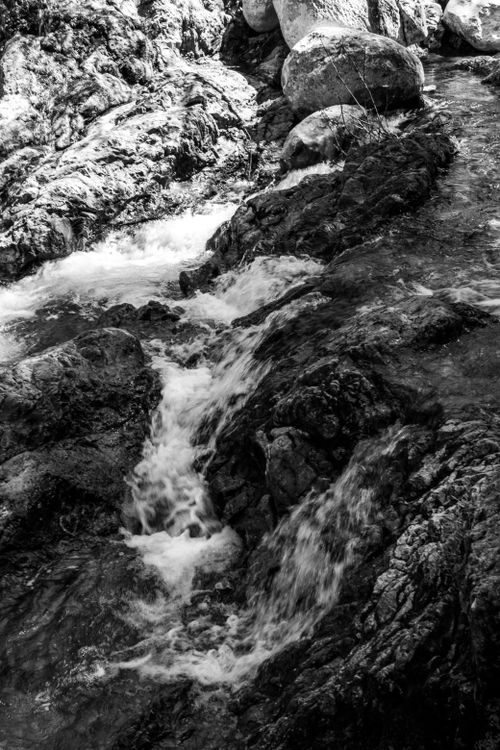 Free A striking black and white image of a rocky waterfall flowing through natural landscapes. Stock Photo