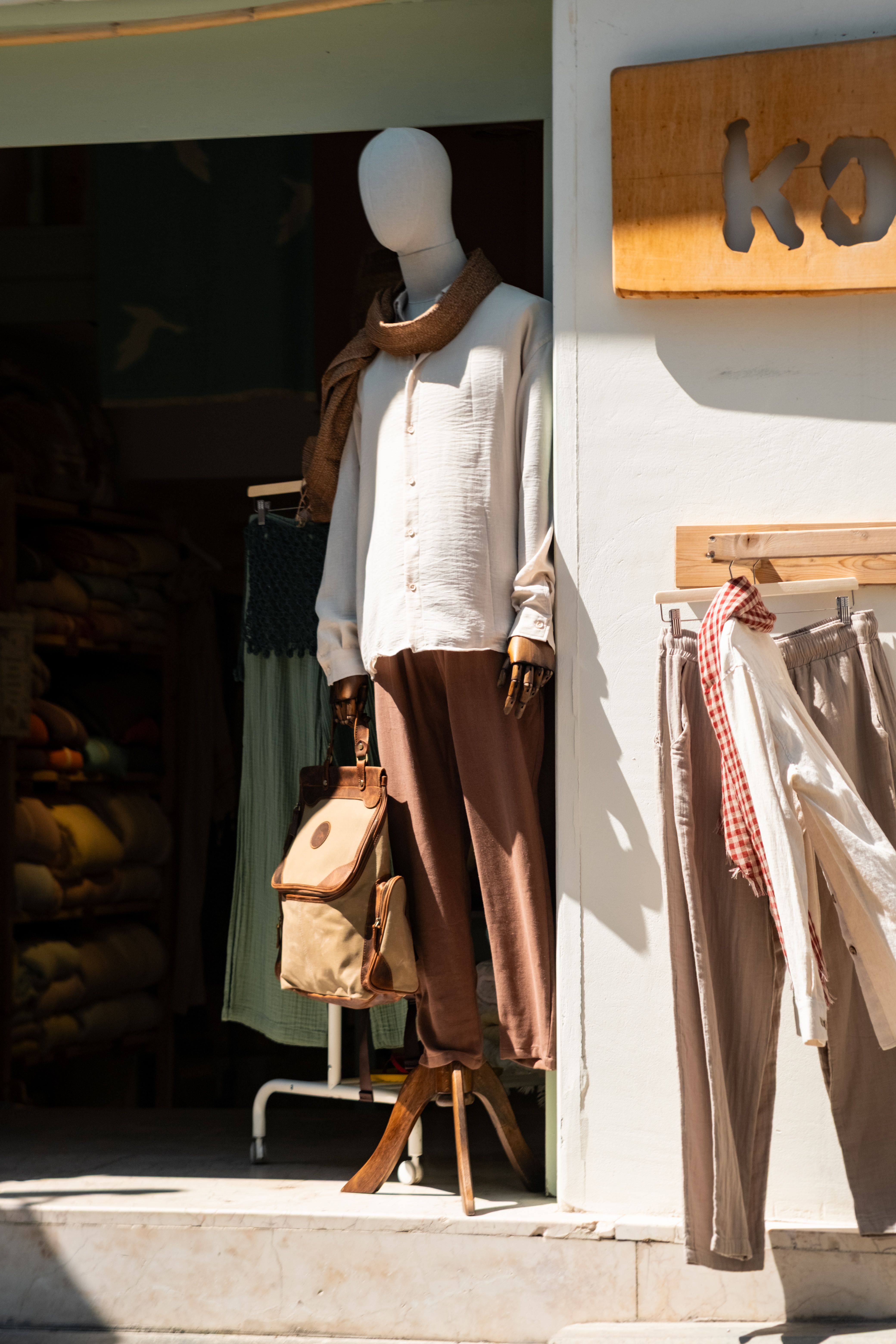 Sunny outdoor fashion boutique display with chic mannequin styling in neutral shades.