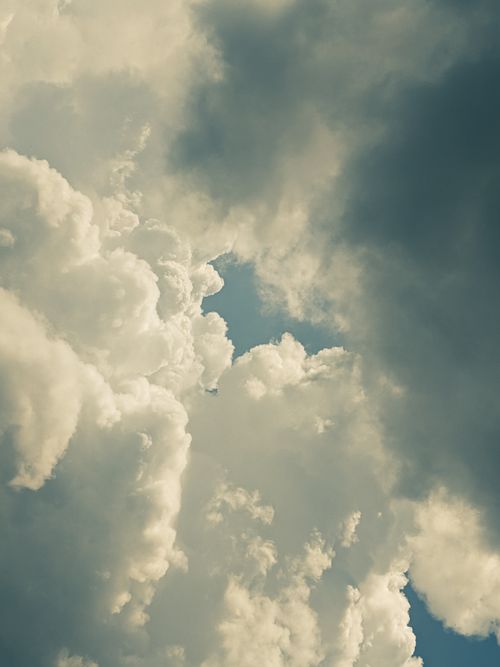 Free An inspiring view of dramatic clouds with sunlight filtering through, offering a glimpse of blue sky. Stock Photo