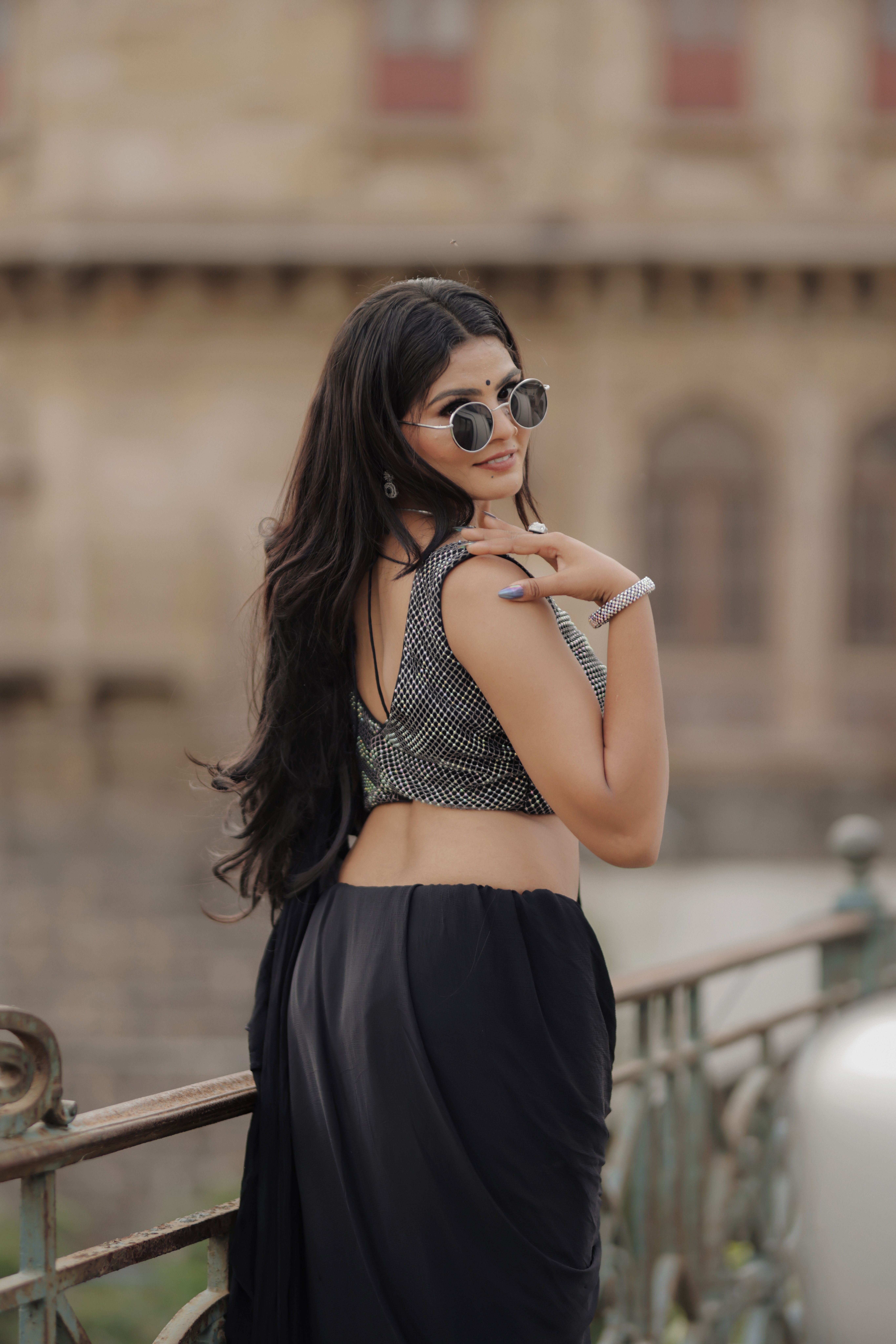 Stylish woman in sunglasses posing confidently against a historic background.