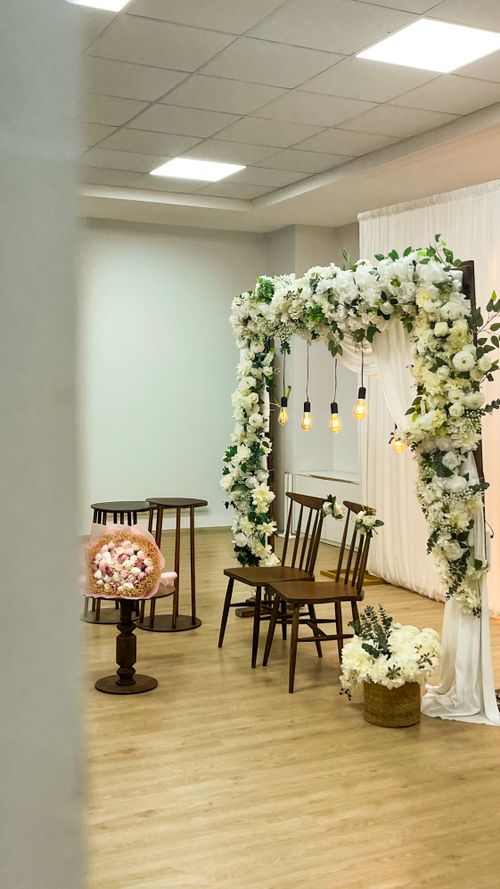 Free Beautifully decorated indoor wedding arch adorned with white flowers and hanging lights. Stock Photo