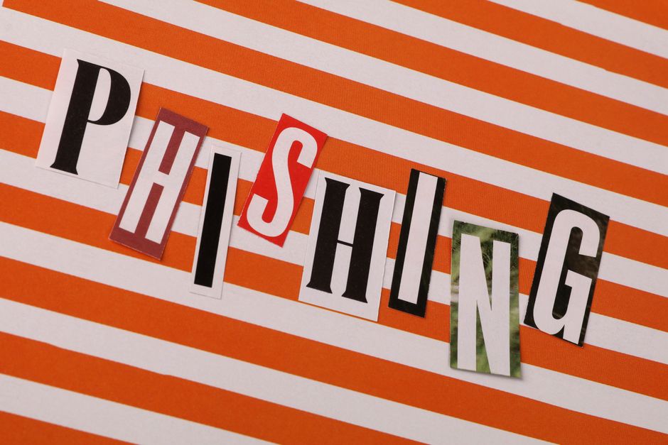 Conceptual image of the word 'Phishing' using cut-out letters on an orange striped background.