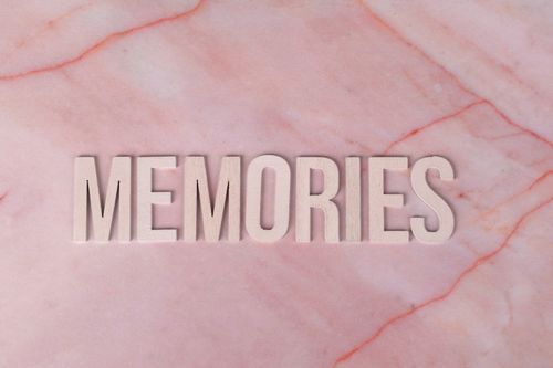 Free Wooden 'Memories' letters on pink marble background. Ideal for nostalgic themes. Stock Photo