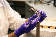 Close-up of a scientist in gloves testing a vacuum tube in a laboratory environment.