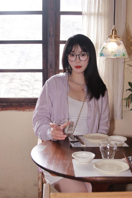 Free A woman enjoys a relaxed moment with a drink at a cozy indoor café in Nanjing, China. Stock Photo
