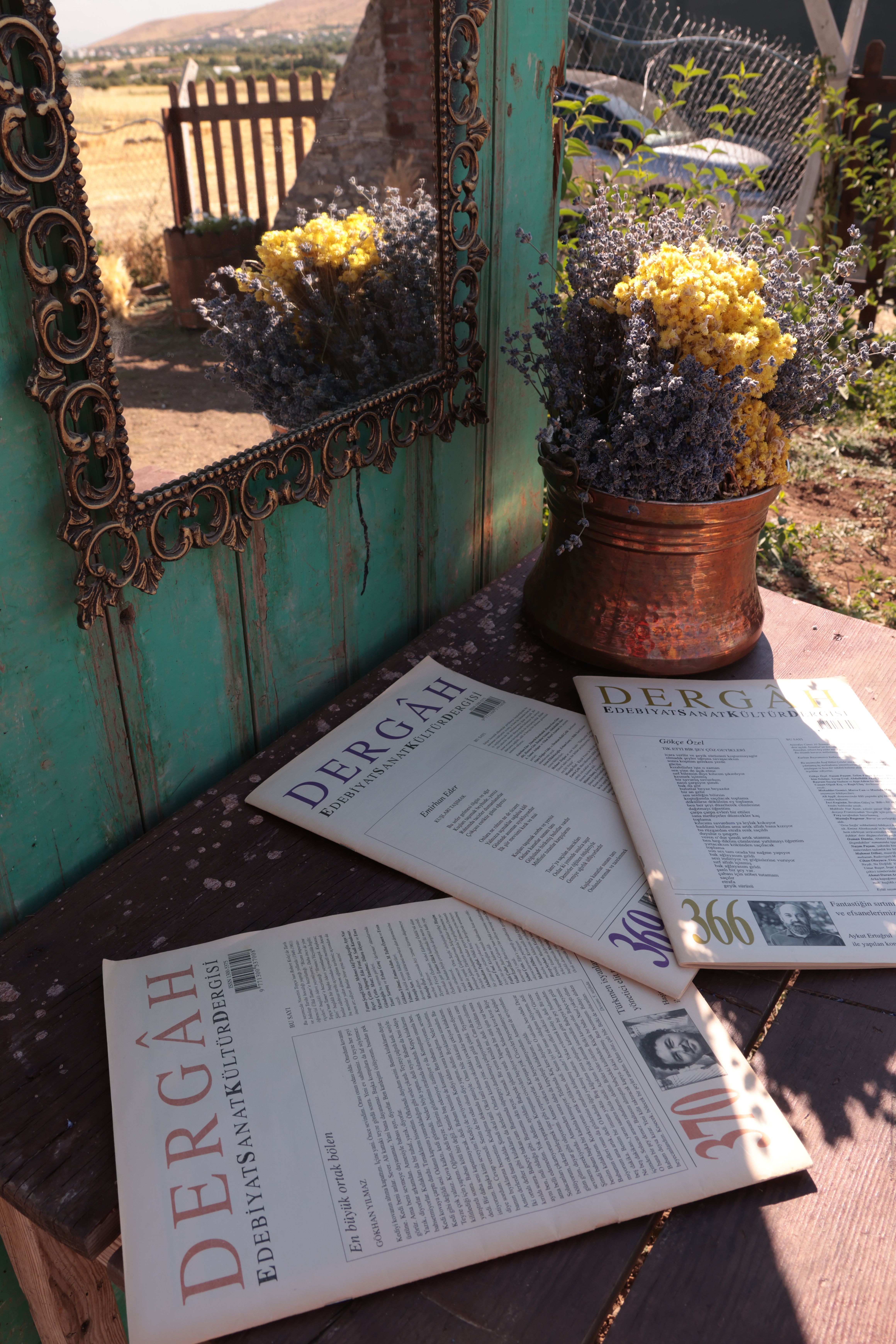 Stylish outdoor setup with magazines and dried flowers in rustic setting.