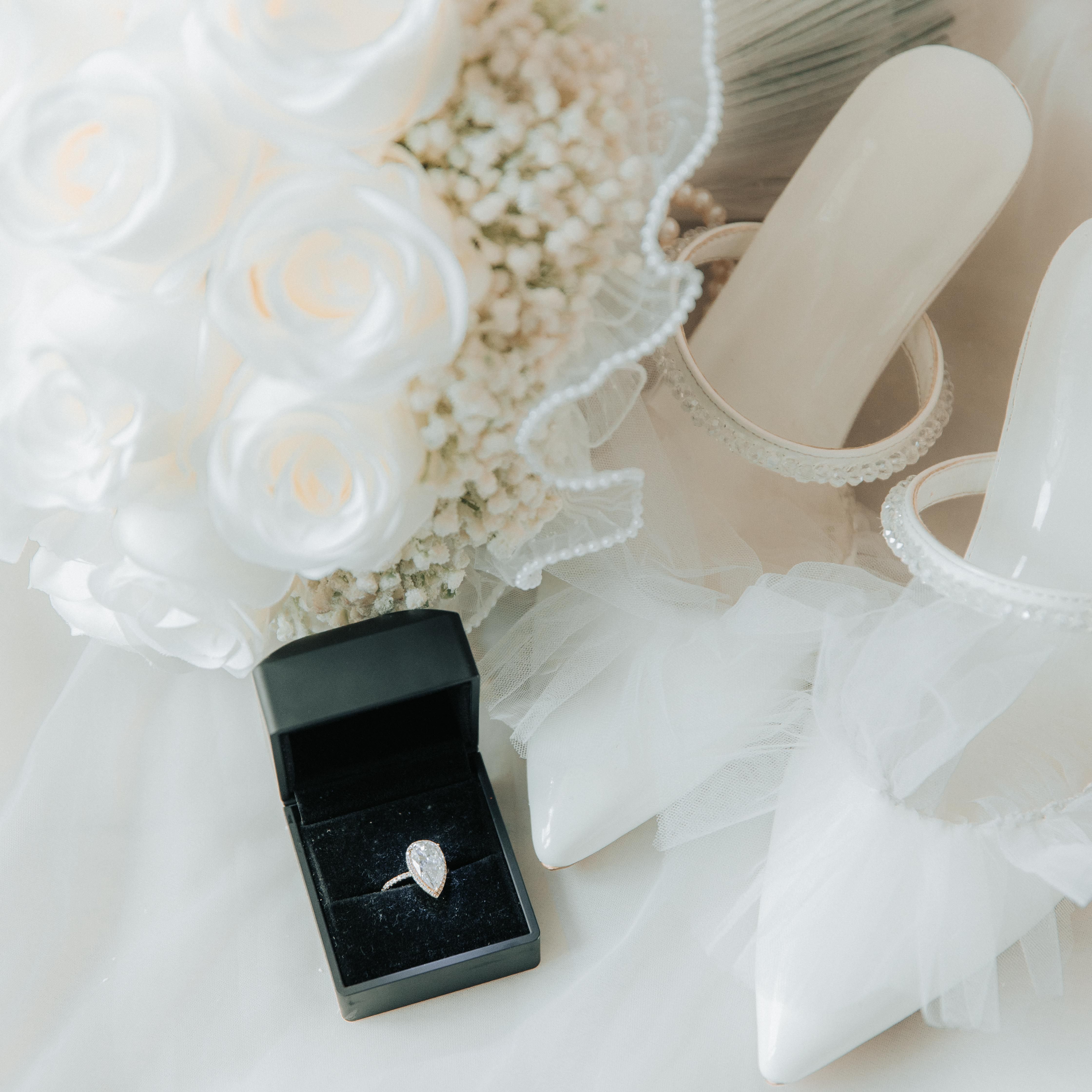 Chic bridal ensemble with wedding shoes, bouquet, and diamond ring ready for a special day.