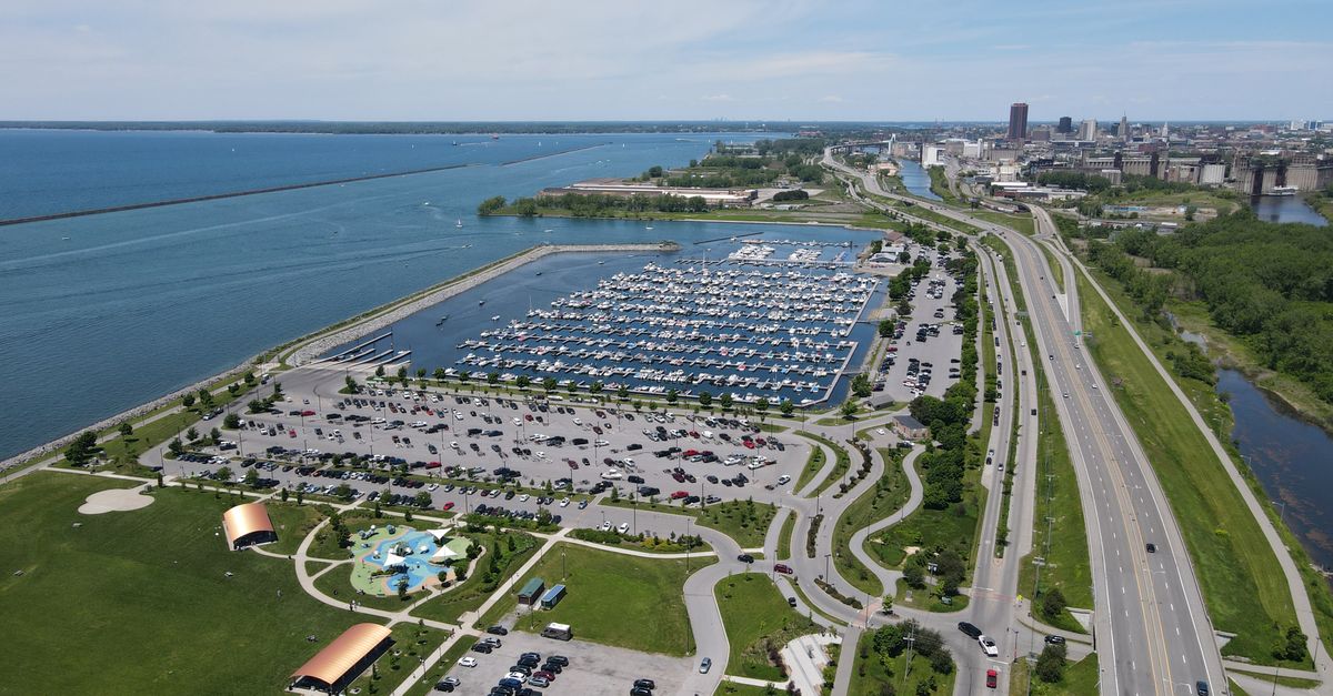 Aerial view of Buffalo waterfront marina and cityscape, showcasing boats, green spaces, and urban environment.
