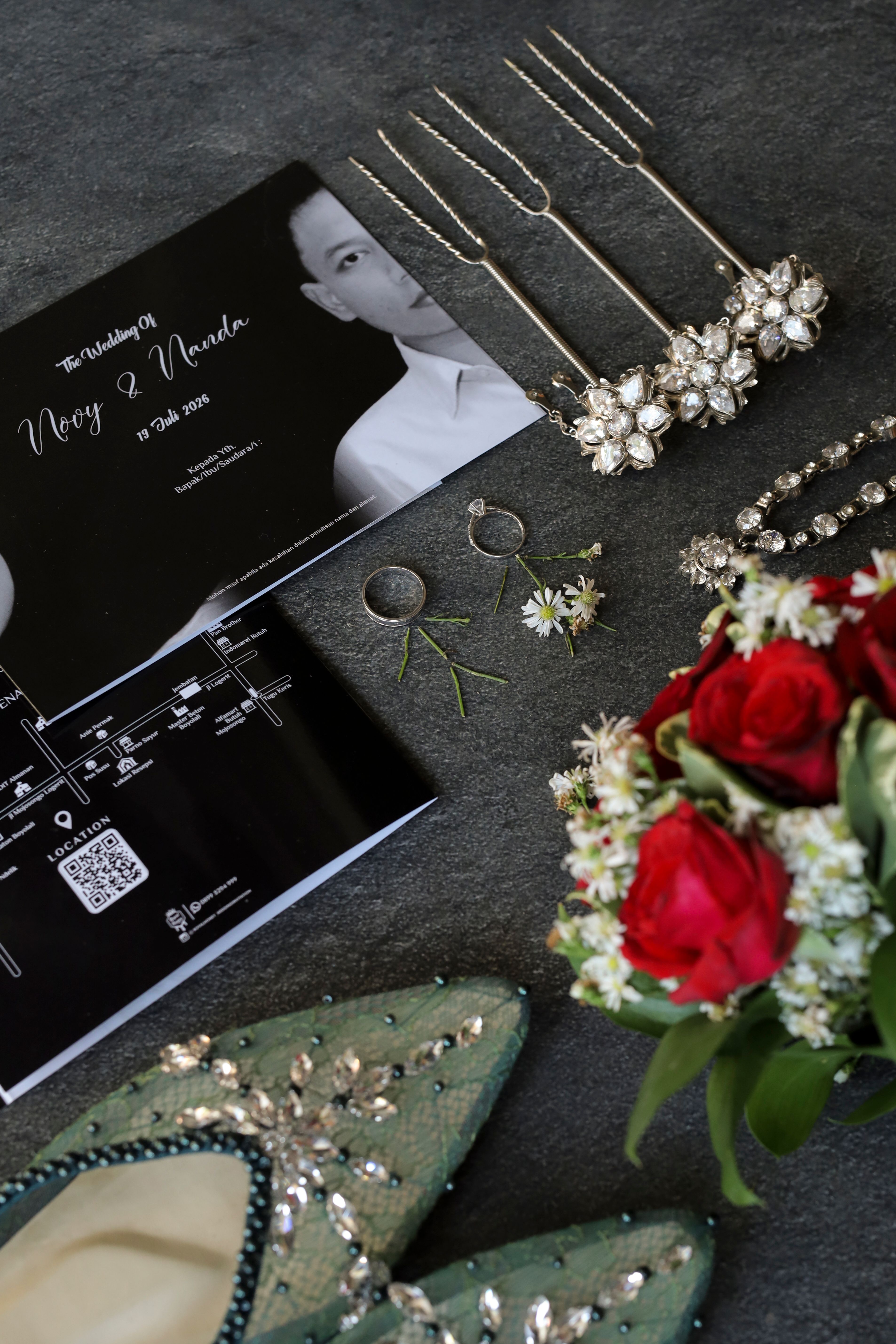 Flat lay of Javanese wedding accessories with floral bouquet and invitation.