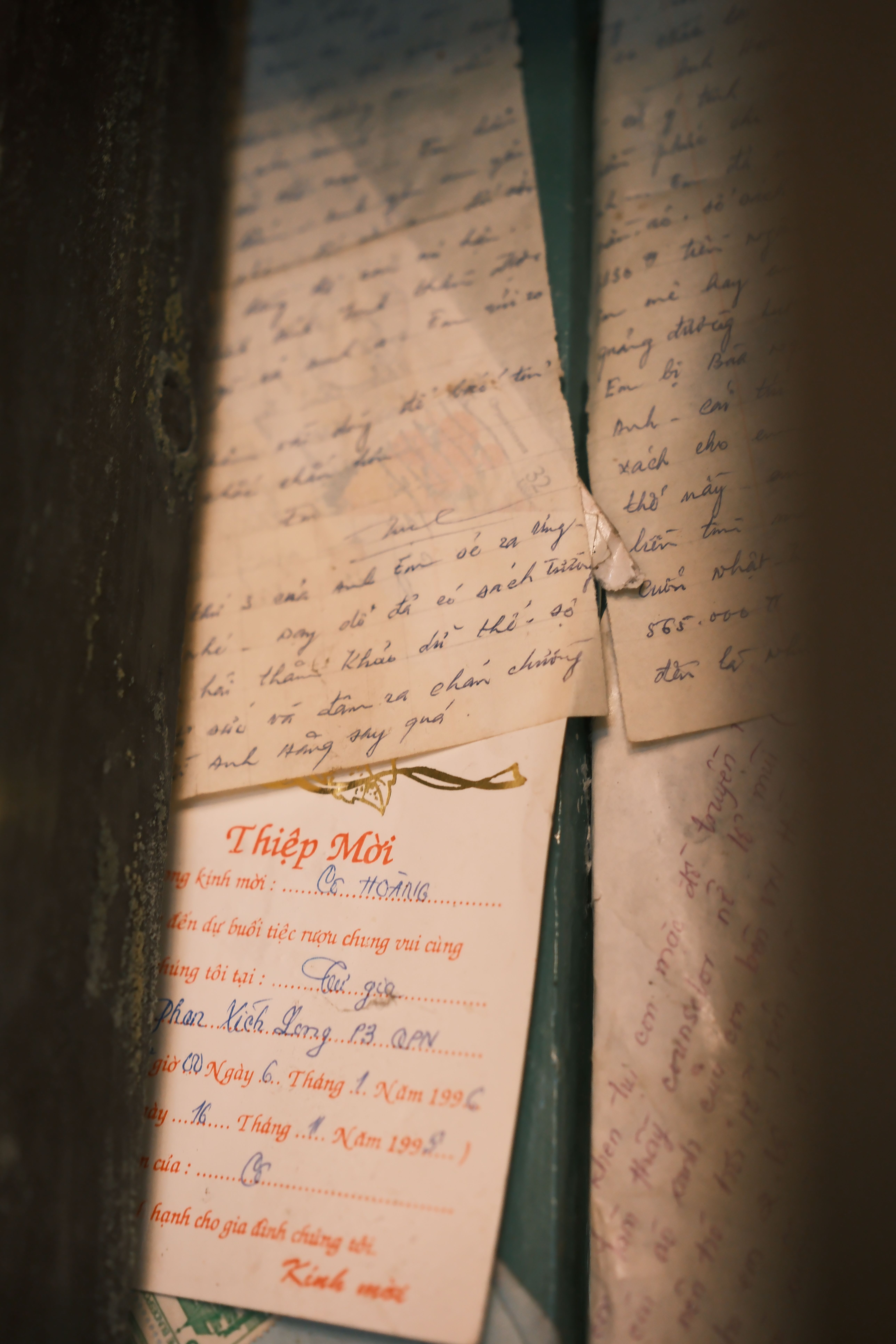Close-up of aged handwritten letters and an old invitation card.