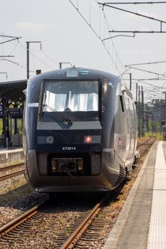 A sleek train approaches Dol-de-Bretagne station on a sunny day in Brittany, France.