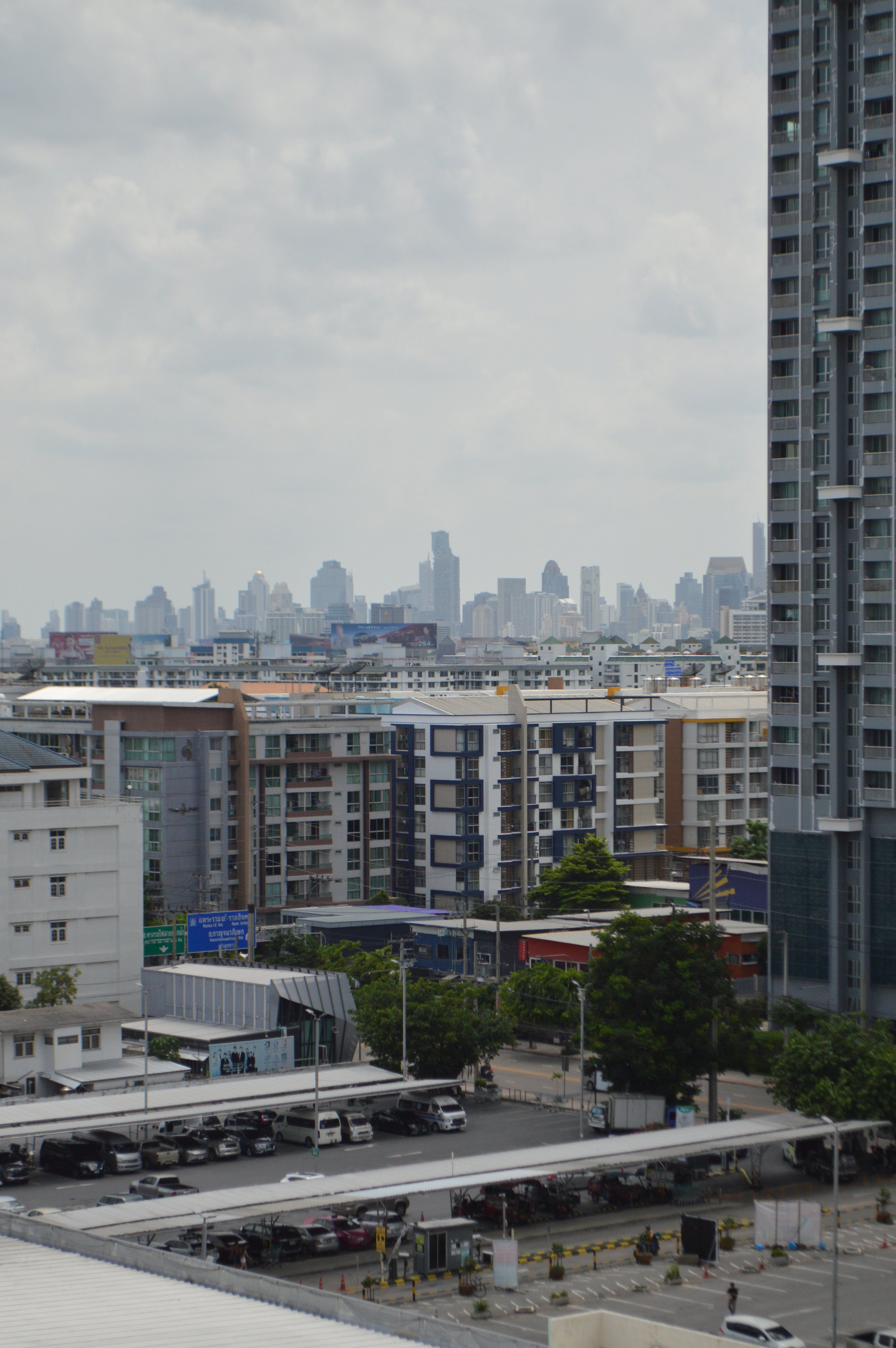 Cityscape featuring modern high-rises and apartment buildings under a cloudy sky.