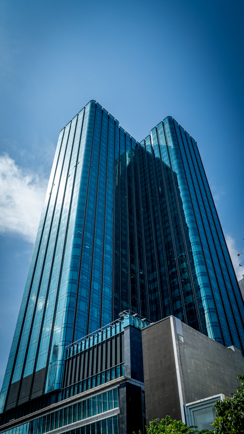 Free Tall blue glass skyscraper with sunny clear sky background. Stock Photo