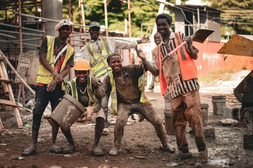 Free Group of construction workers in high spirits at an outdoor construction site. Stock Photo