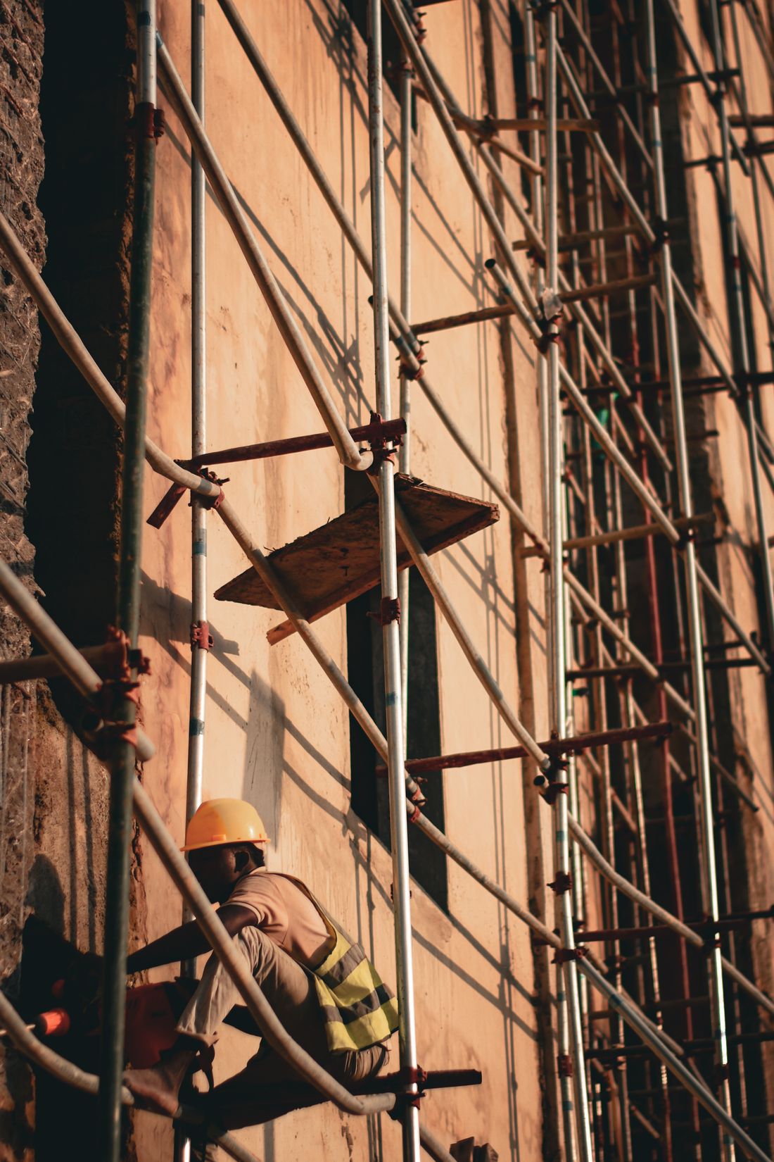 Construction worker climbing scaffolding at an active building site