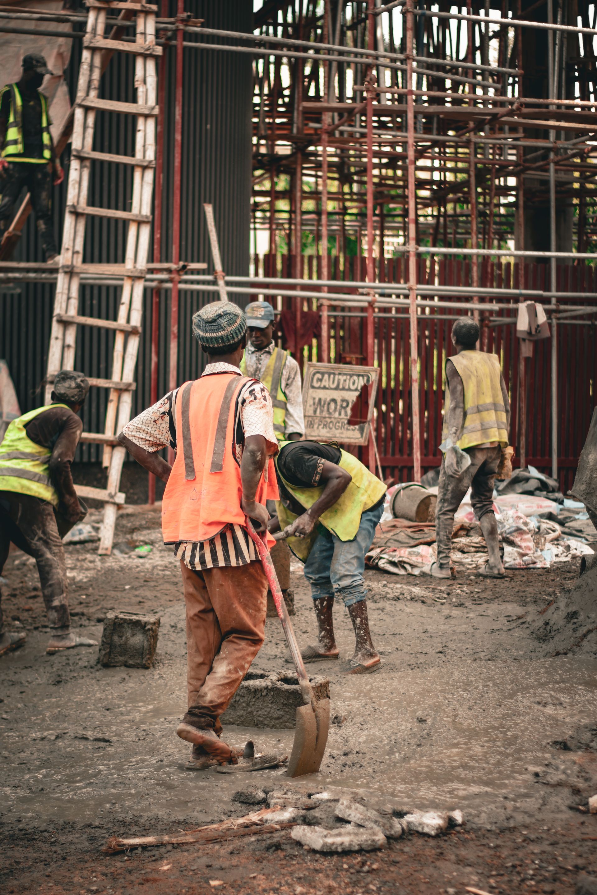Construction workers in safety gear on site with scaffolding