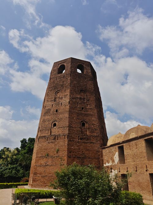 Free Explore the ancient tower in Murshidabad, West Bengal with lush surroundings under a clear sky. Stock Photo