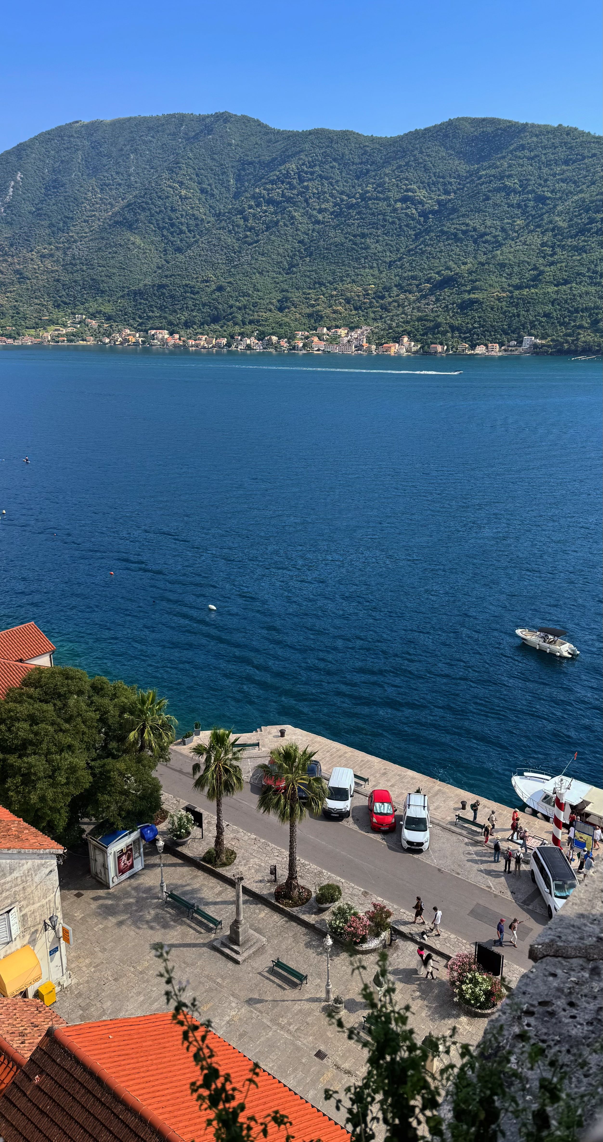 Fotomural Un pintoresco pueblo costero en Karadağ, con exuberantes colinas y aguas azules en un día despejado.