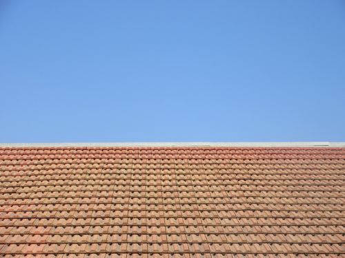 Free Terracotta roof tiles under a clear blue sky, capturing architectural simplicity and outdoor tranquility. Stock Photo