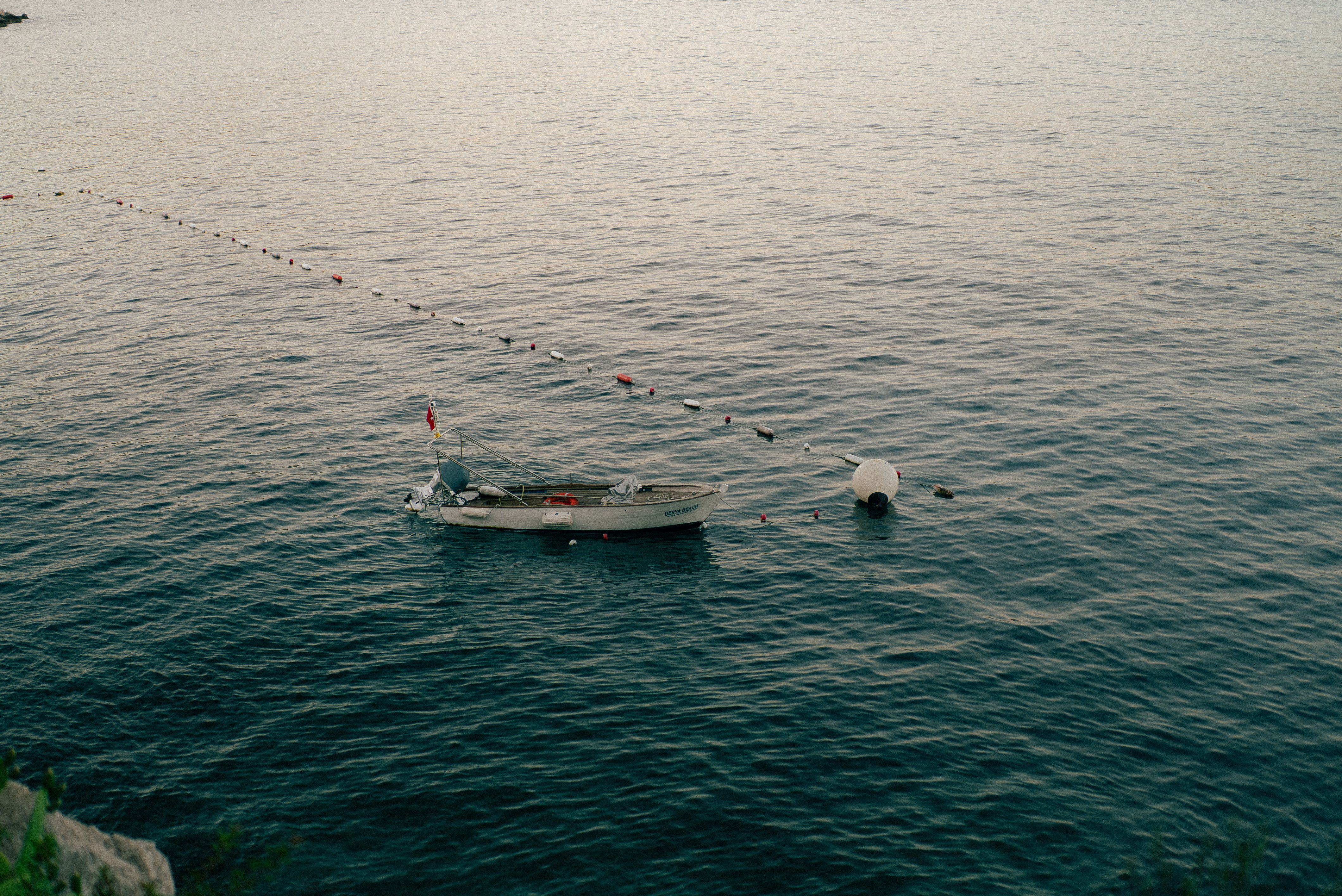A calm boat drifts in the tranquil sea near Antalya, Türkiye, during the evening.