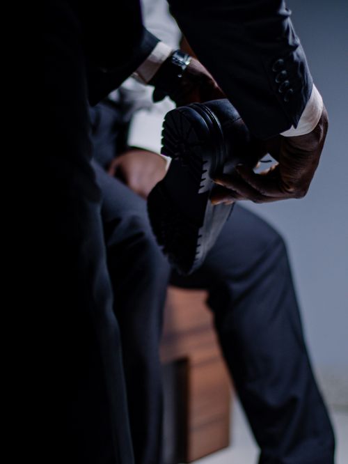 Free A close-up of a businessman in a sleek suit polishing his shoes, emphasizing elegance and professionalism. Stock Photo