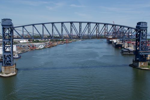 Free Aerial view of a large steel lift bridge spanning an industrial river or canal on a clear day. Stock Photo