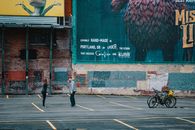 Side view full length faceless man and woman in outerwear standing face to face on asphalt ground near bicycles against shabby brick wall